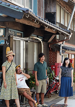 写真:ゲストハウスの外にいる大川さん夫妻と、男性1名・女性1名のお客さん。