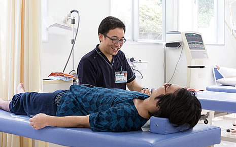 写真:患者さんの右手を膝に乗せて施述している石本さん。